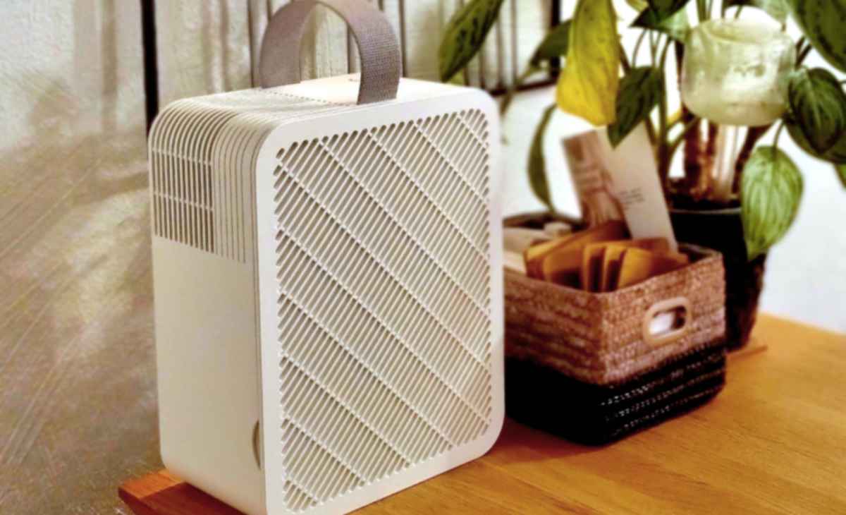 White IKEA UPPÅTVIND air purifier standing on a table beside houseplants